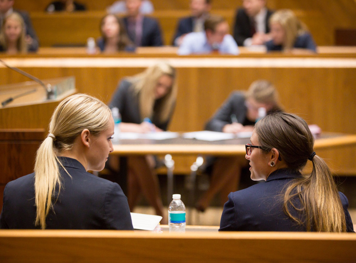 Two students talk in the courtroom at the law school