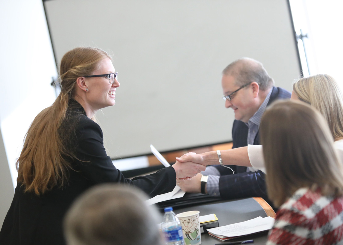 A female law student shakes hands with a client