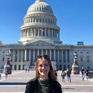A female law student poses for a picture in front of the U.S. Capitol building.
