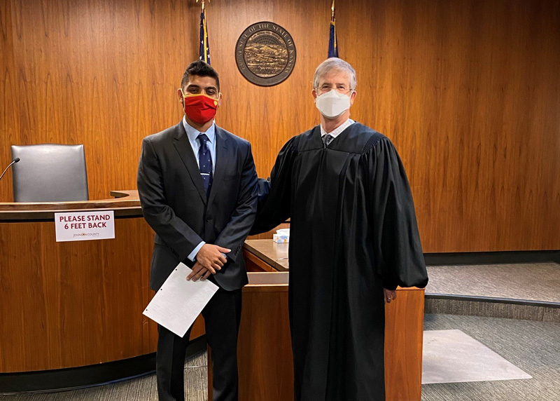 A student poses with the judge he is interning with in a courtroom