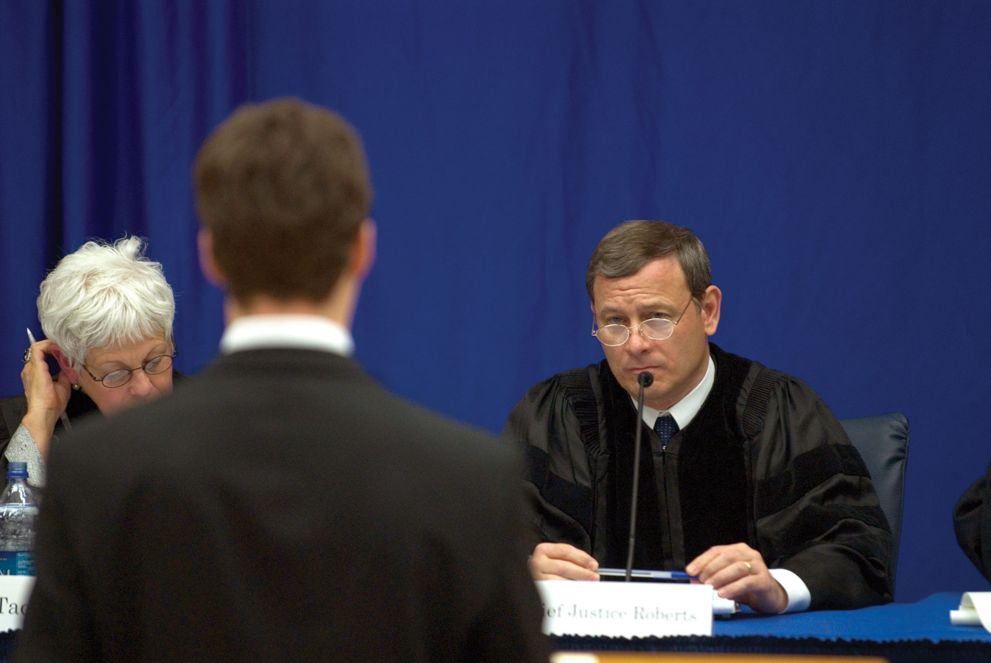 Chief Justice John G. Roberts judges a moot court competition at KU Law. Judge Roberts is pictured in front of a blue background. 