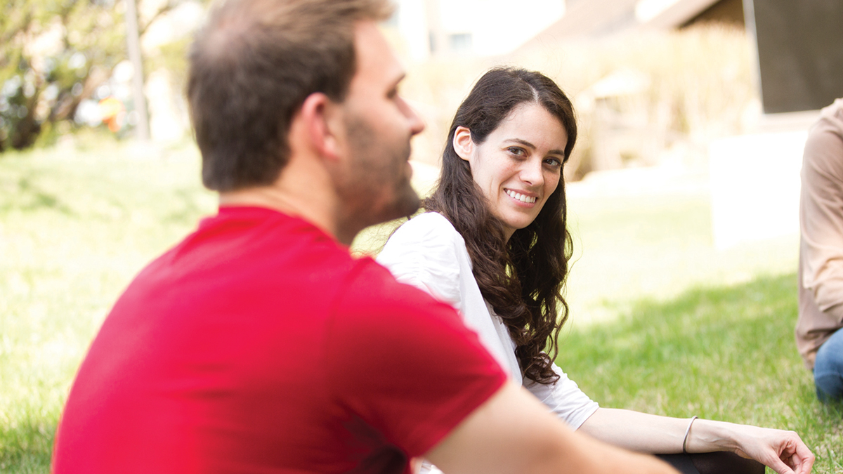 A female student smiles at a classmate during an outdoor class meeting