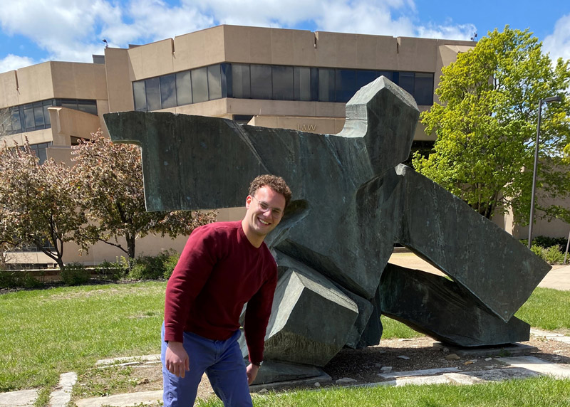 Student Ambassador Andrew Arbuckle poses at the Tai Chi Statue in front of Green Hall