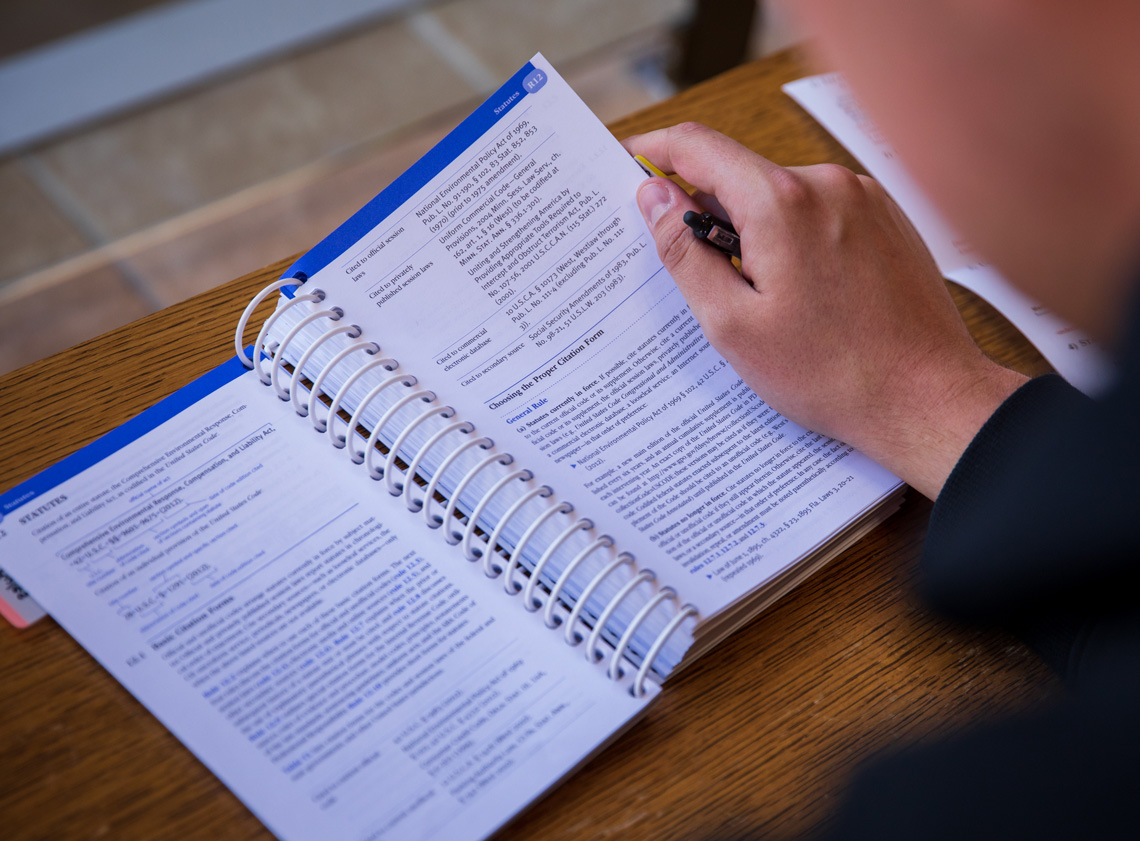 A student turns a page in the Bluebook citation guide