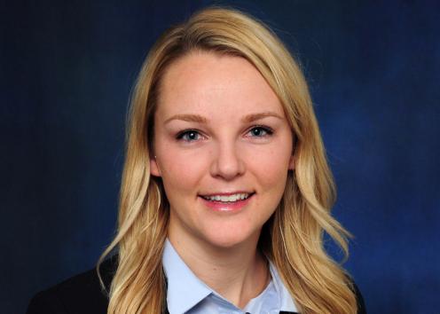 A headshot of Ashley Akers in front of a blue backdrop. 
