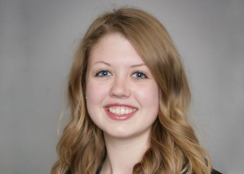 A headshot of Cara Beck in front of a gray backdrop. 