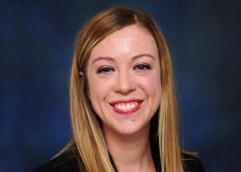 A headshot of Sara Fevurly in front of a blue backdrop. 