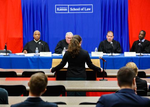 A law student argues a moot court case in front of a panel of judges